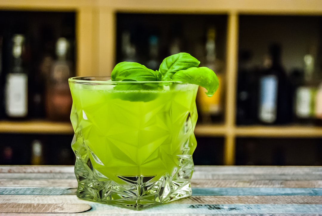 rock glass filled with green liquid, A twist to the classic Whiskey Smashed that substitutes American Whiskey for gin an