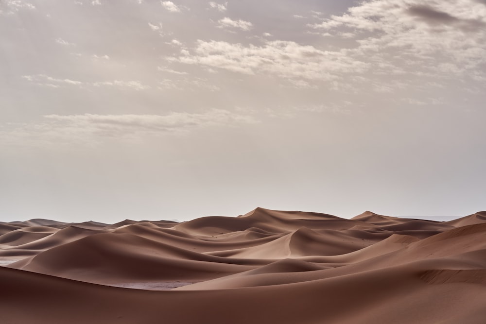 白い雲の下の茶色の砂漠