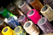 Several rolls of colorful decorative tape are neatly arranged in rows, each with a unique pattern and vivid colors. The tapes are mounted on metal rods, creating an appealing display that highlights the variety in design.