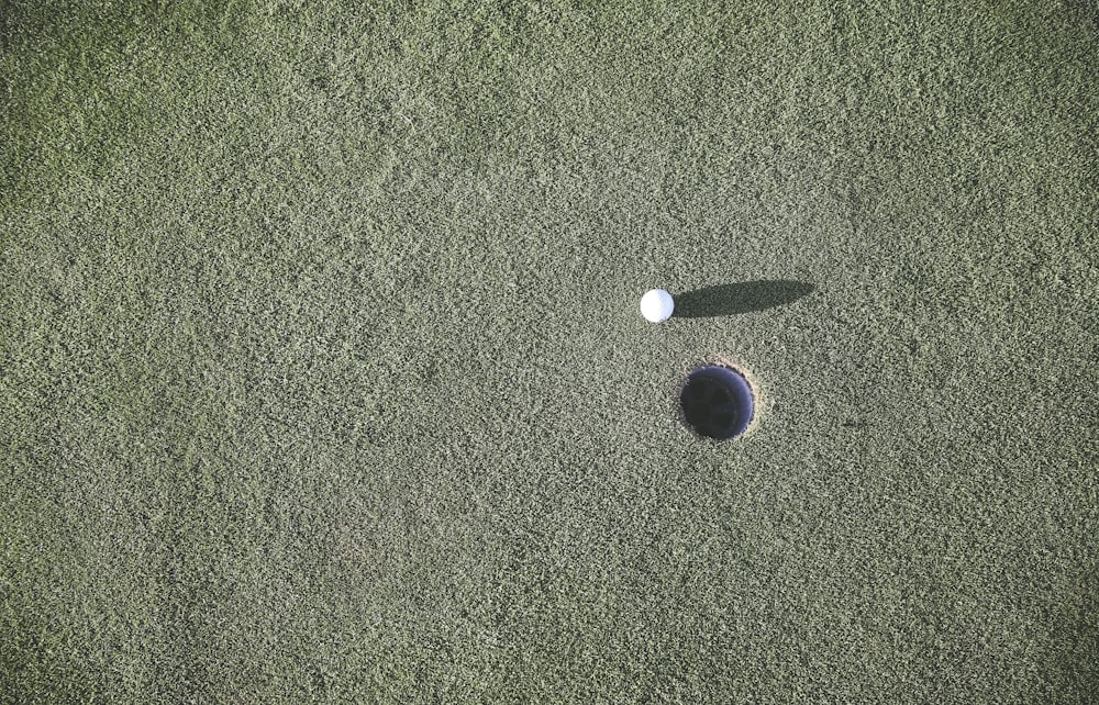 Pelota de golf blanca cerca del hoyo