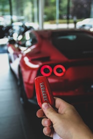 red person with keyfob of red Ferrari supercar