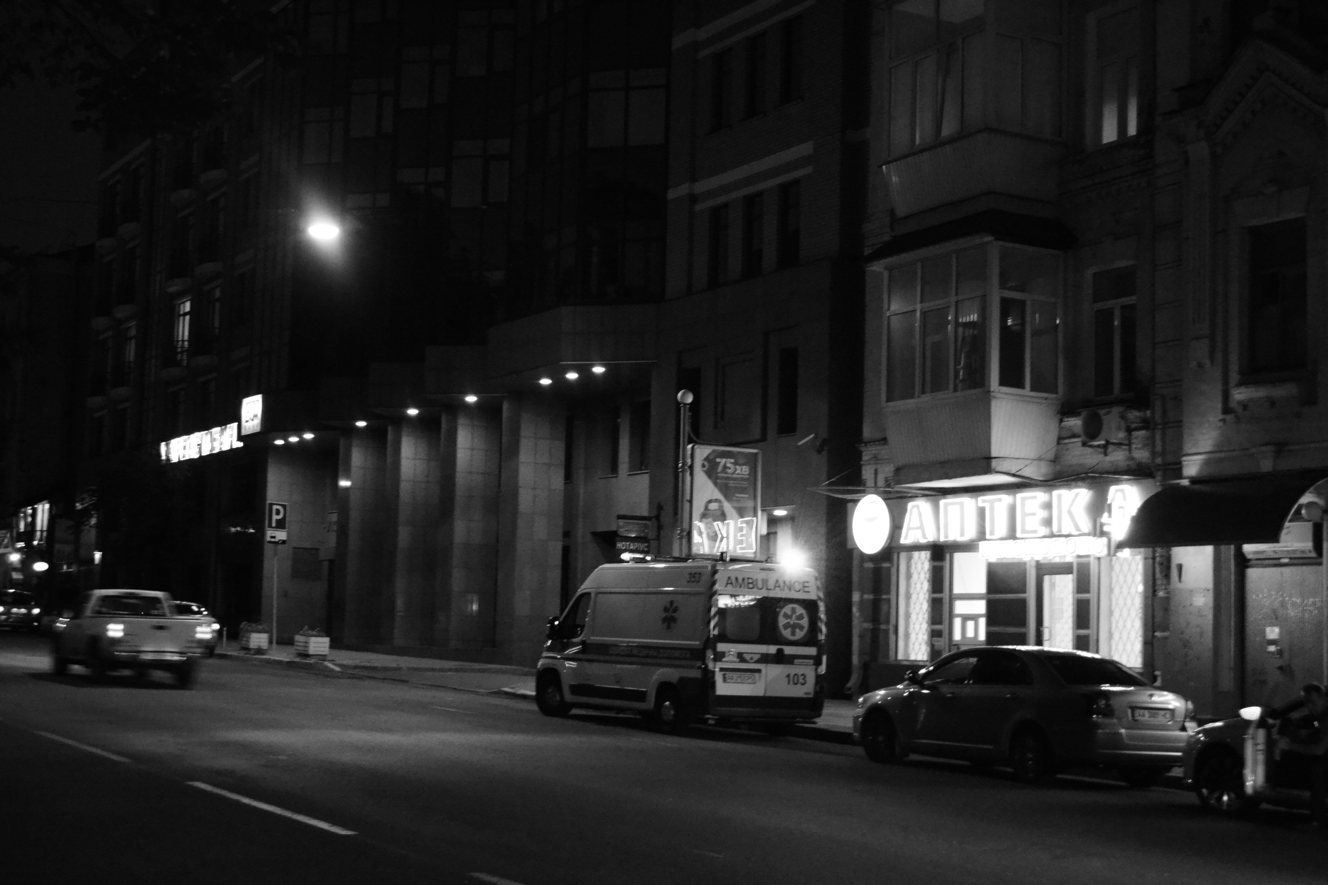 Ambulance parked at industrial site entrance at dusk, emergency vehicle lighting, dark industrial backdrop