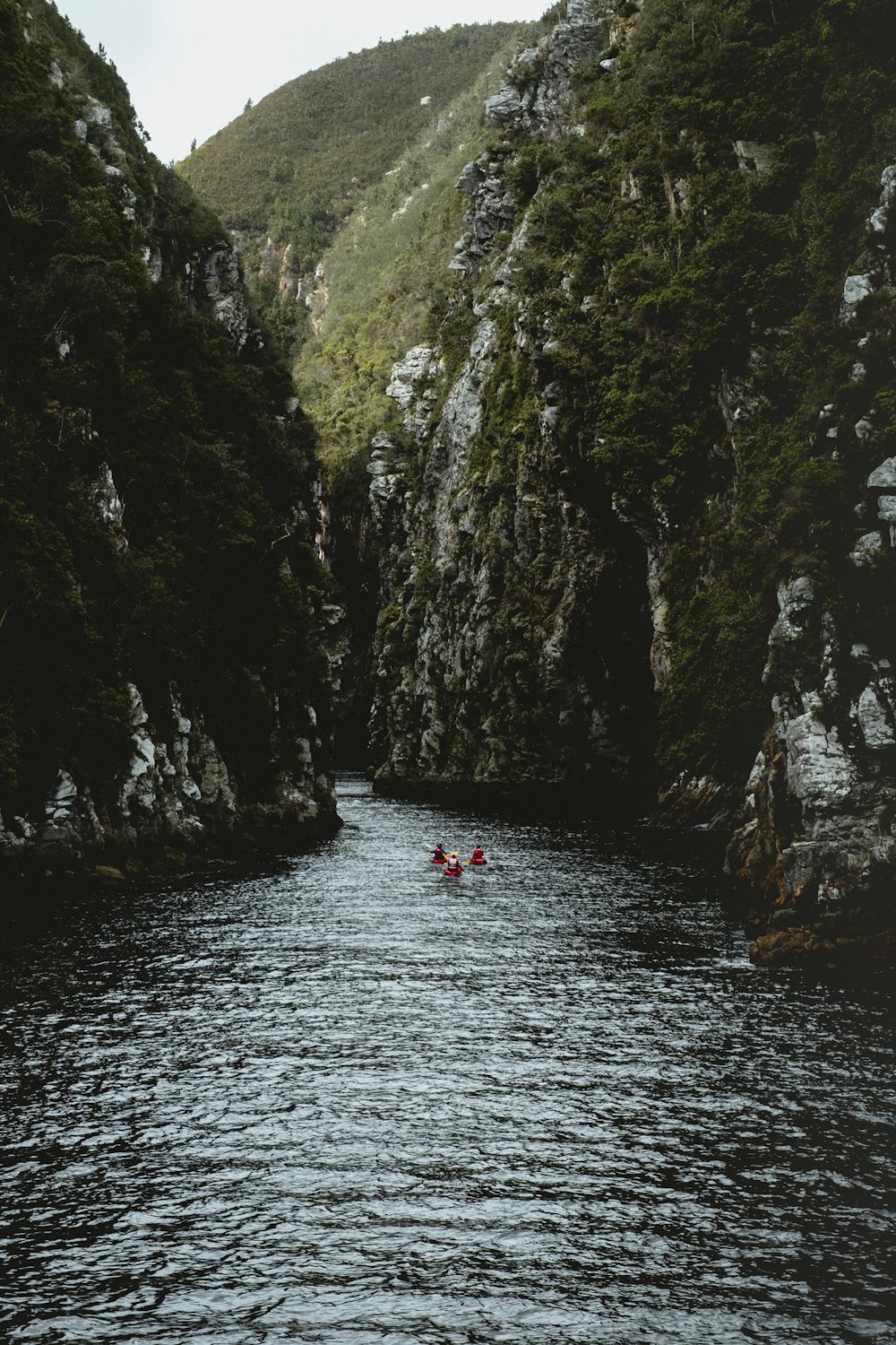 people in river between mountain gorge