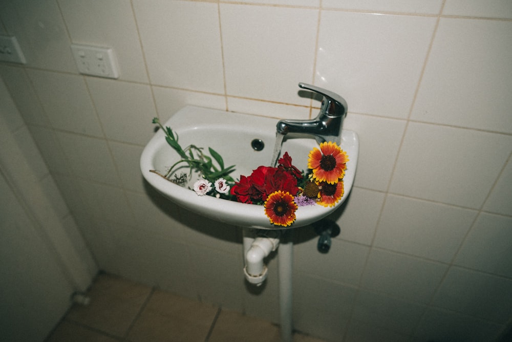 Variedad de flores en fregadero de pedestal de cerámica blanca