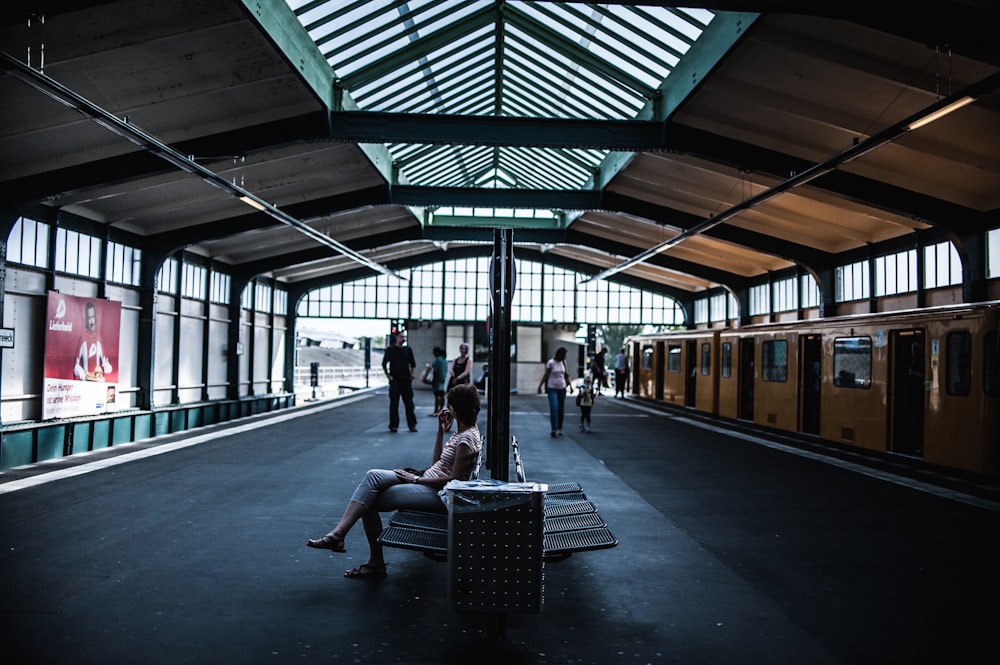 Frau sitzt auf Stuhl im Bahnhof