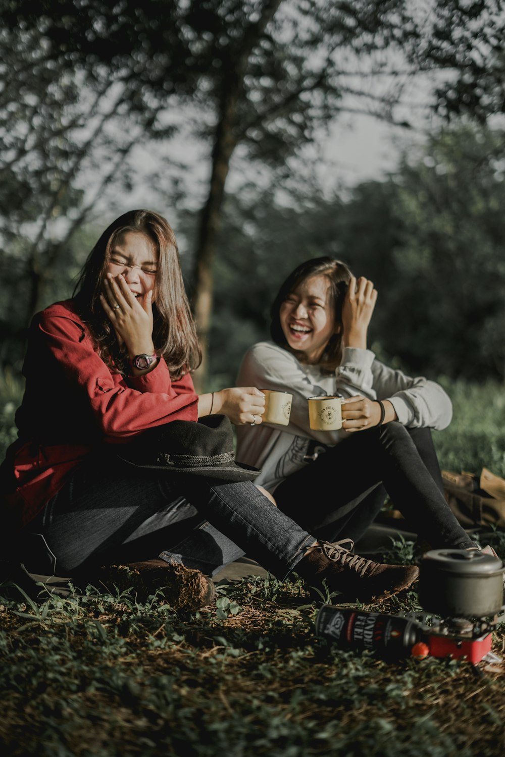 two women holding cups laughing at each other