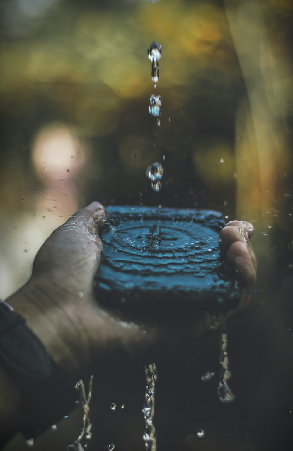 person holding smartphone with water drops