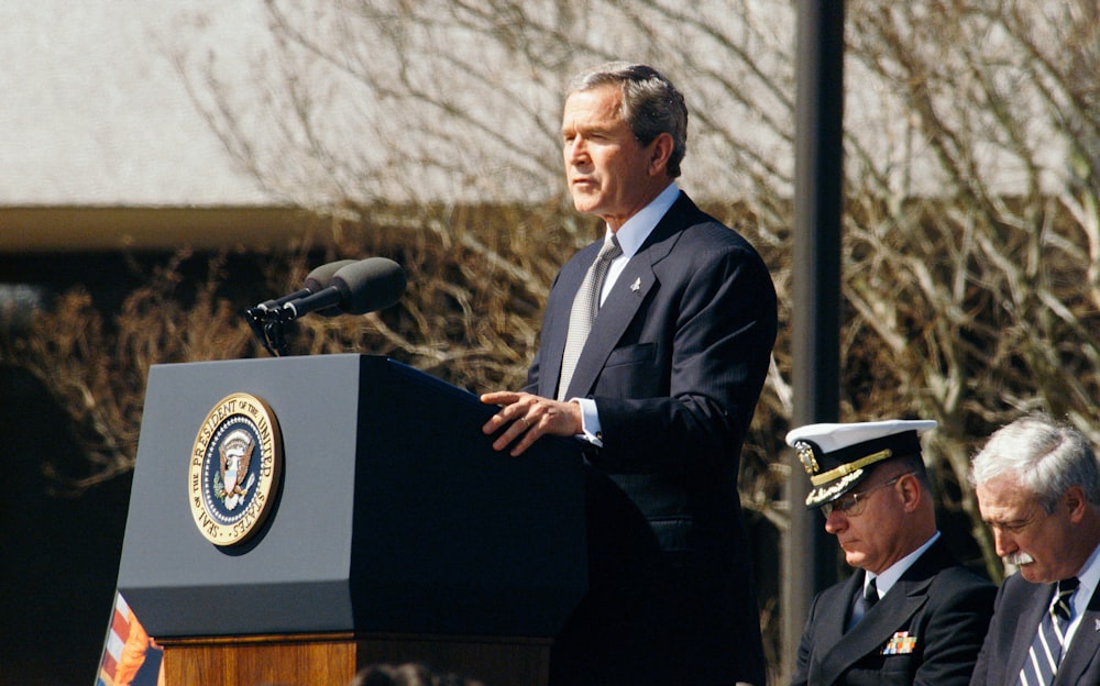 George W. Bush em pé na tribuna durante o dia