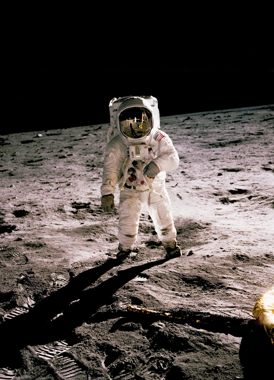 Photo of an astronaut, on the moon, facing camera, others reflected in his visor