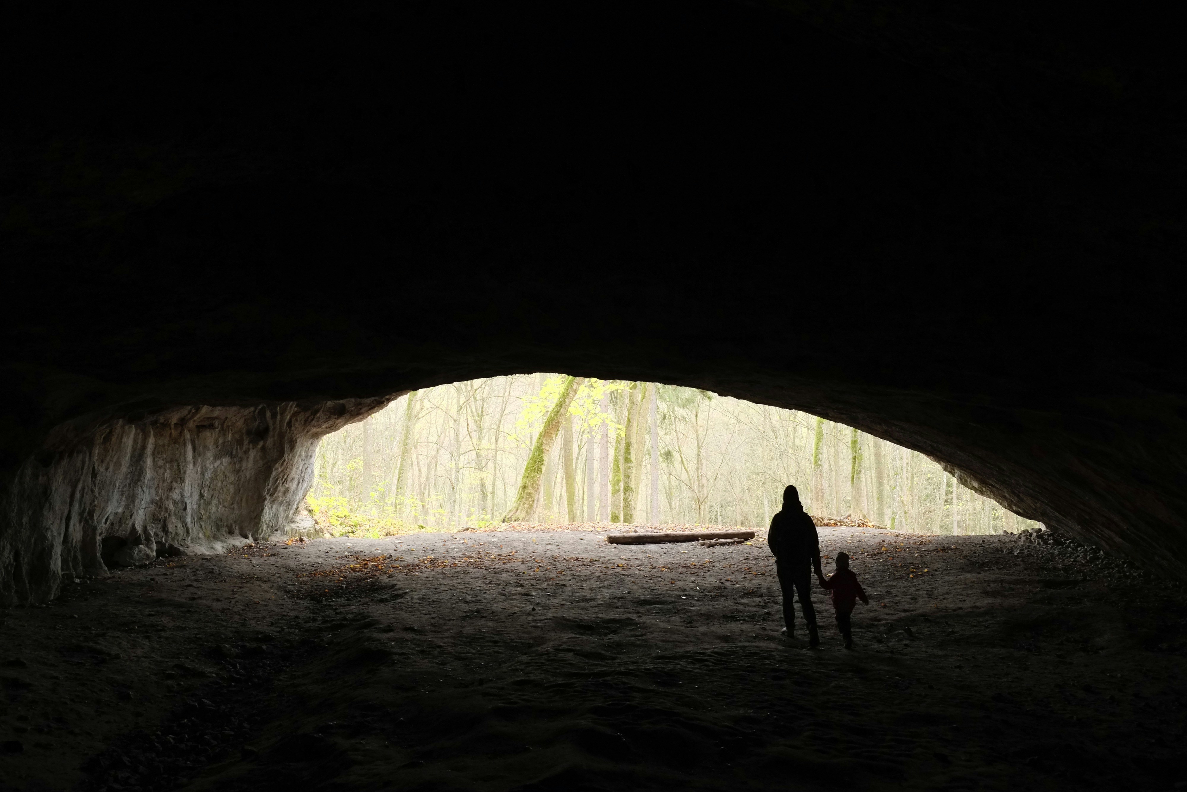silhouette of person and child in cave, adventure in cave with bats