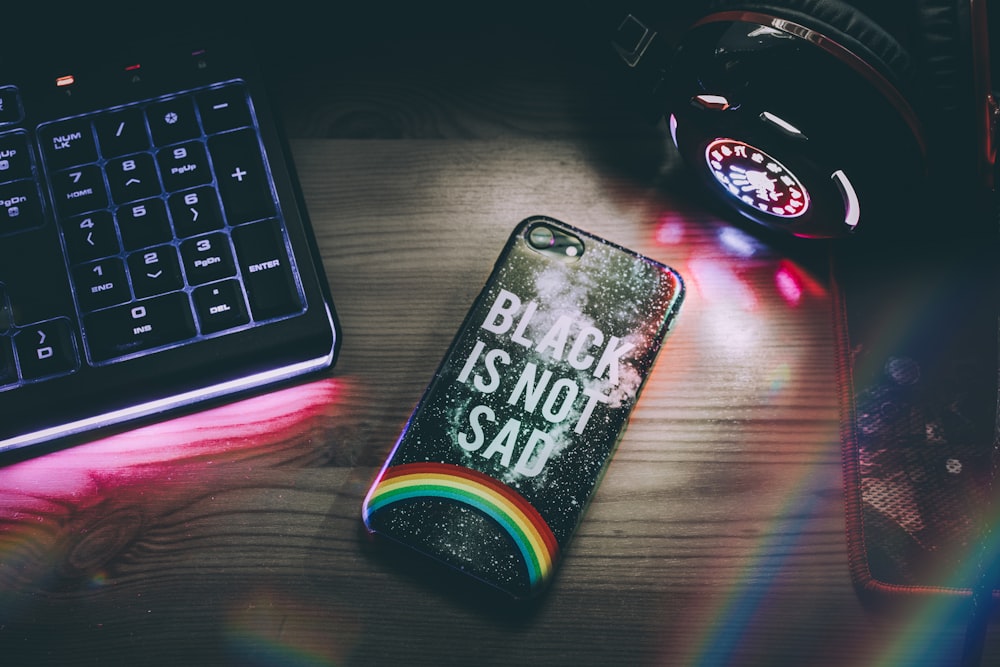 black smartphone beside keyboard