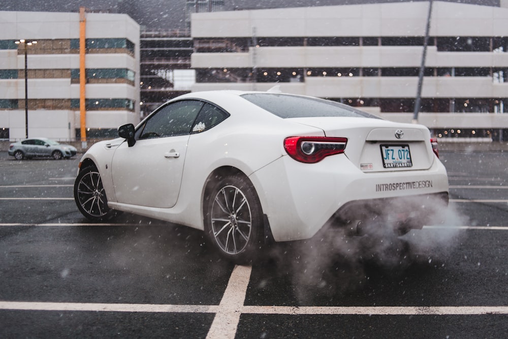 white coupe on road near white buildings