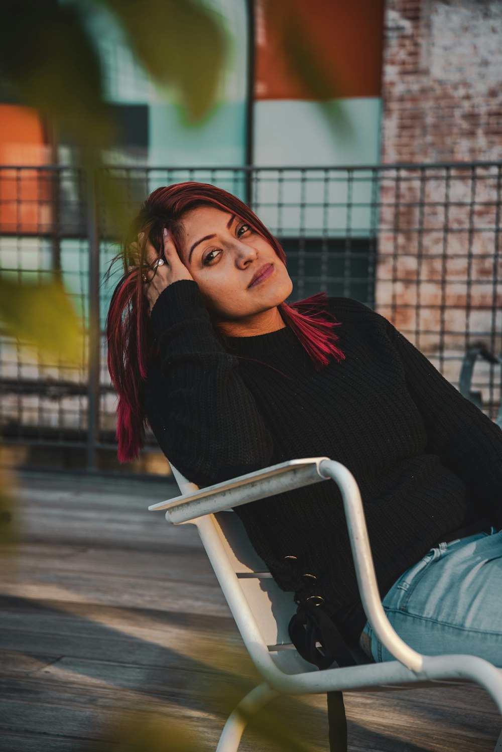 woman in black knitted sweater sitting on white armchair holding her head