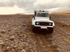 A rugged off-road vehicle climbing a rocky hill with dusty terrain