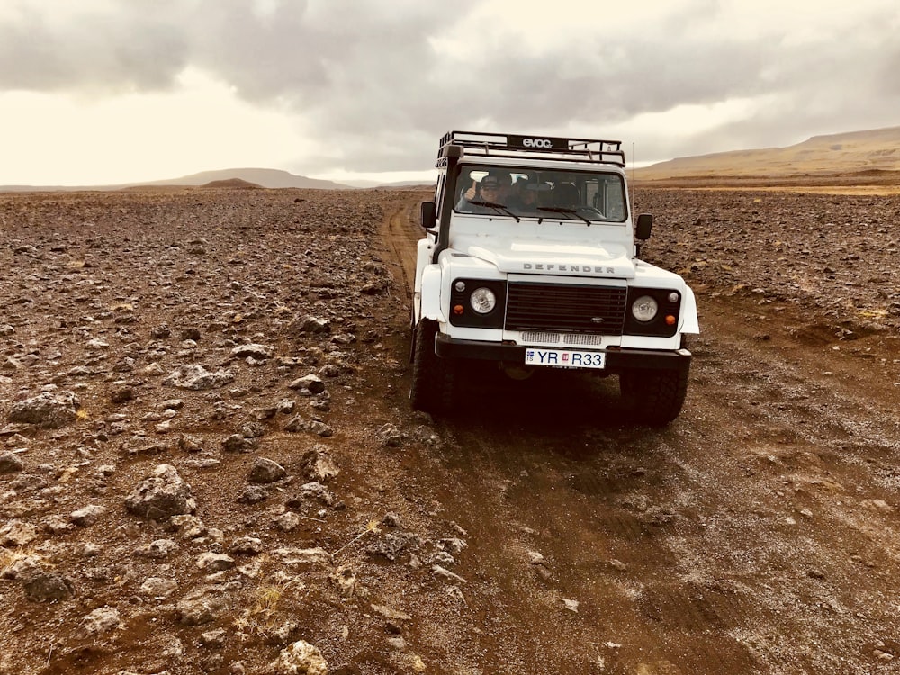 white vehicle crossing dirt road during daytime