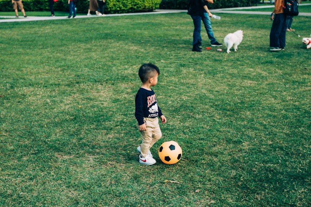 boy playing soccer on grass field