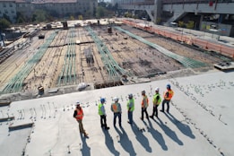 seven construction workers standing on white field