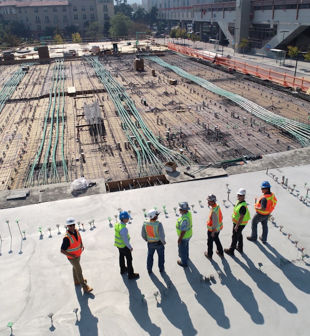 seven construction workers standing on white field