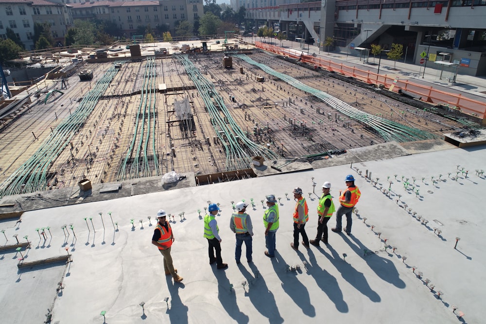 Sete trabalhadores da construção civil em pé no campo branco