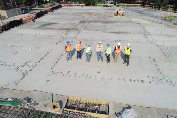 A safety consultant reviewing construction site plans with workers wearing hard hats and safety vests.