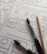 Several sheets of paper feature sketch-style website wireframes drawn with black marker lines. Two black markers and a wooden pencil rest on top of the papers, giving the scene a creative and informal touch.