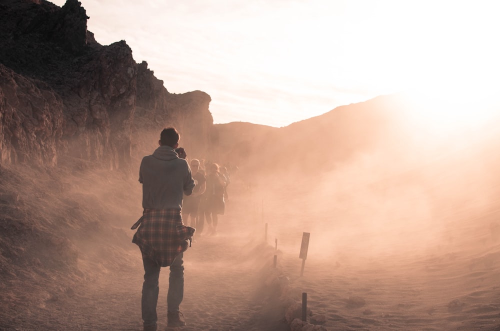 man in gray top standing near mountain