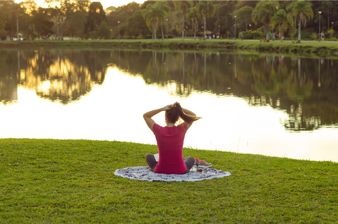 woman sitting on mat in front of body of water