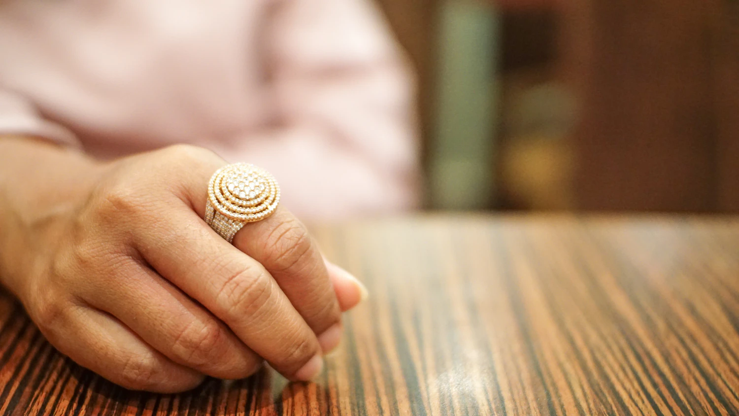 A closed hand wearing the Bricco dome ring in 18k gold, currently sold out, photographed at macro in late afternoon light