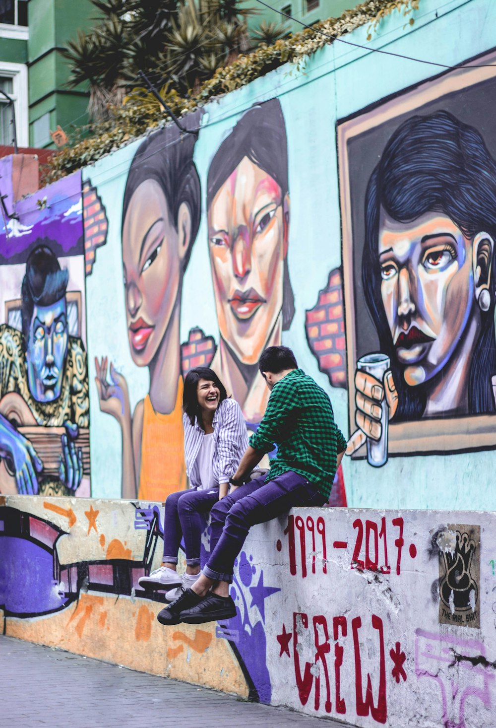 man and woman sitting near wall while laughing with each other