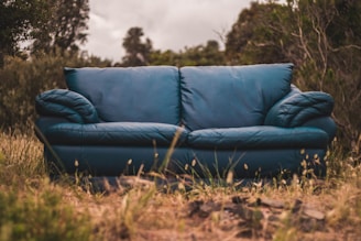 A cozy outdoor sofa with deep blue ShieldCushion covers under a sunny sky.