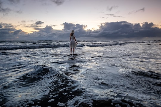 woman standing on seashore during sunrise in Muriwai New Zealand