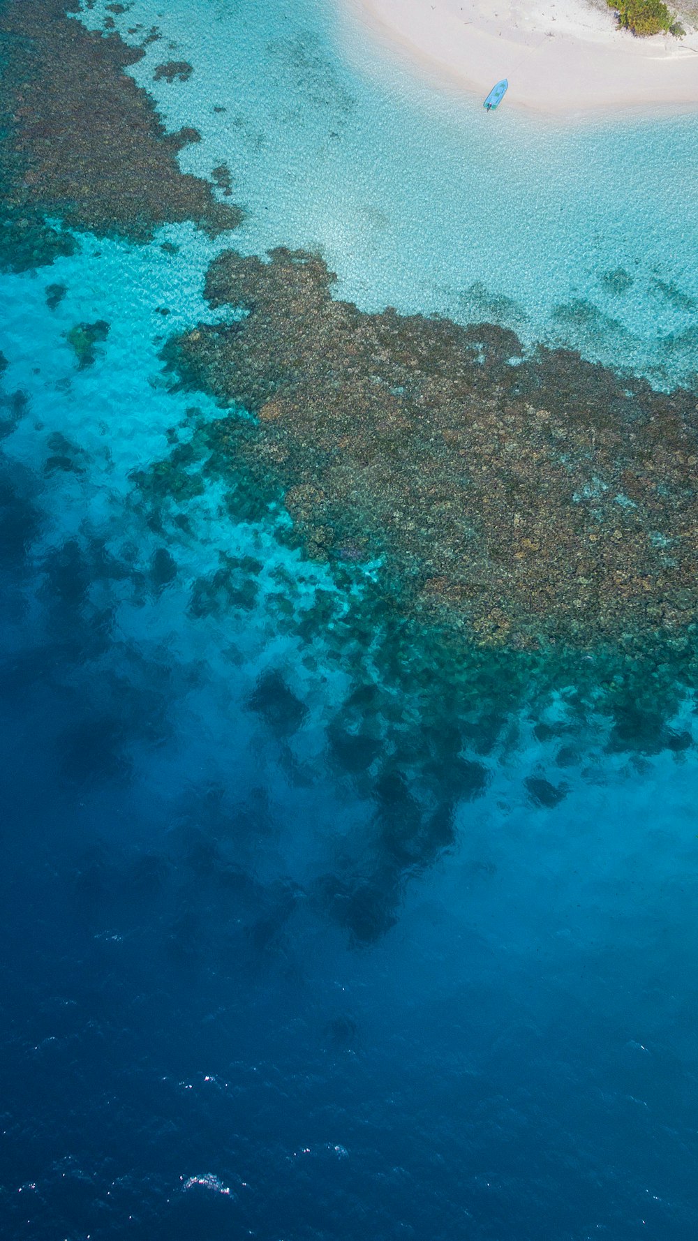 Una vista aérea de un arrecife de coral frente a la costa de una isla tropical