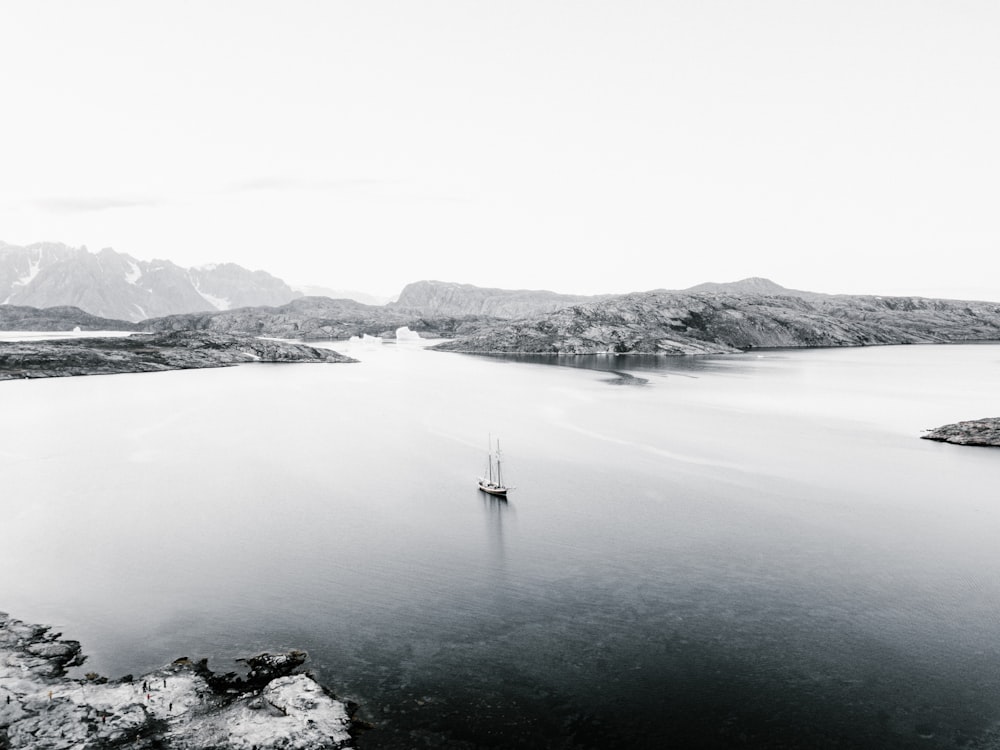 grayscale photography of boat near mountain