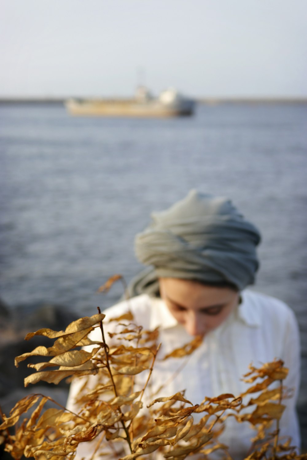 woman in white shirt behind brown leaves selective focus photography