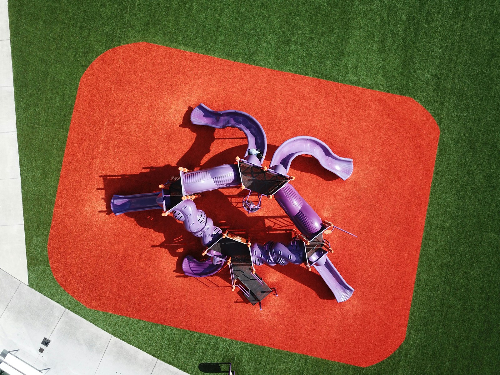 A playground structure on red rubber safety surfacing, seen from above