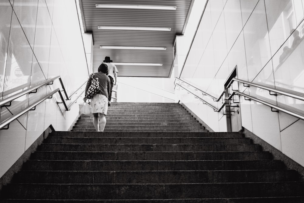 grayscale photography of woman walking on stair