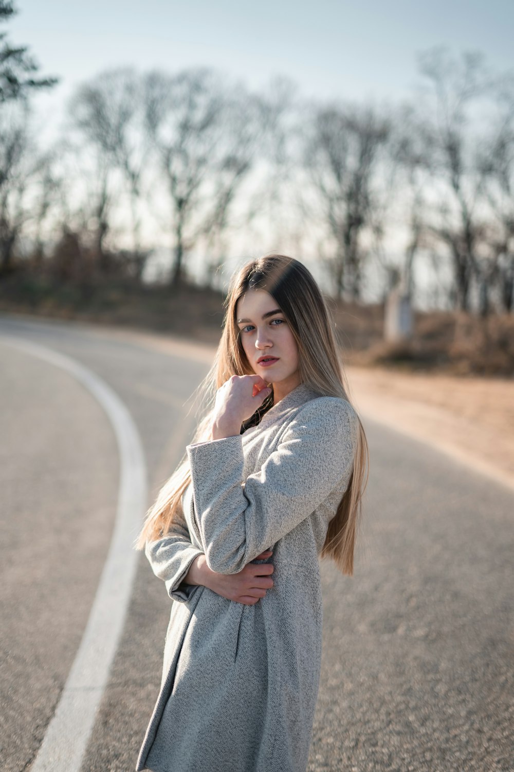 woman standing on road near bare trees