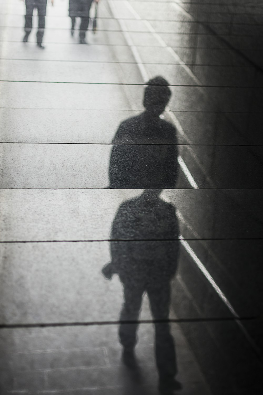 a shadow of a man walking down a sidewalk
