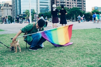 man holding multicolored flag and puppy during daytime