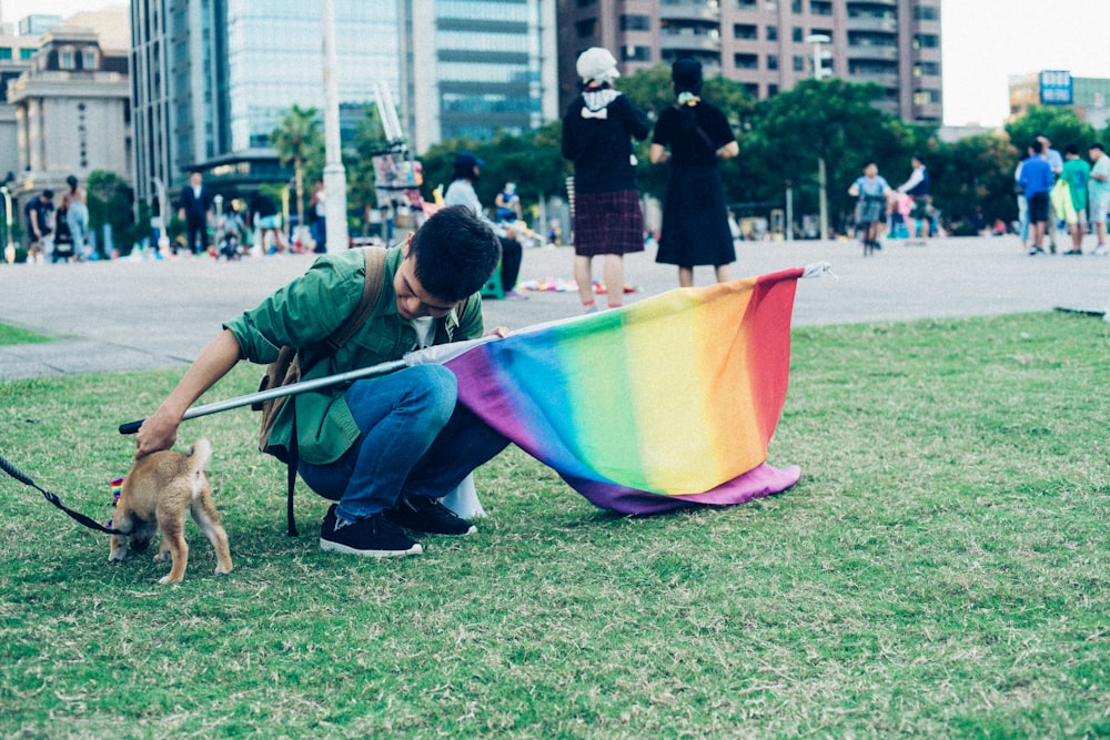 homme tenant un drapeau multicolore et un chiot pendant la journée