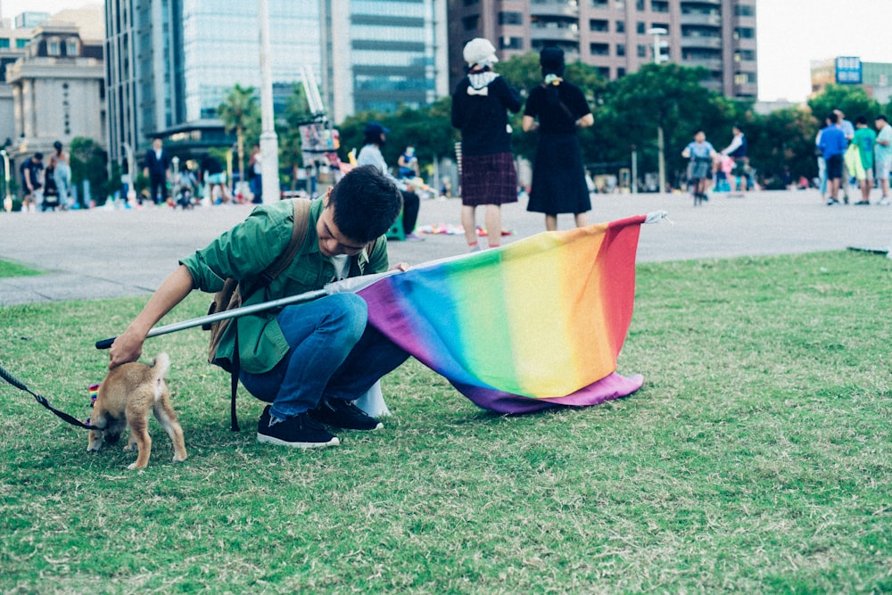 homem segurando bandeira multicolorida e filhote de cachorro durante o dia