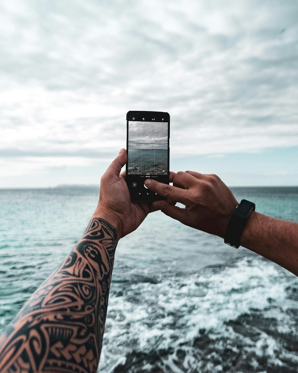 person taking photo of calm sea