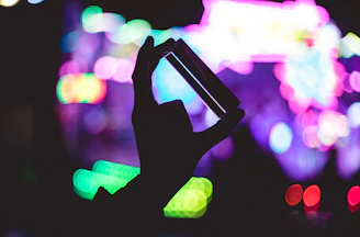 Close-up of hands exchanging a smartphone with a glowing neon-blue background.