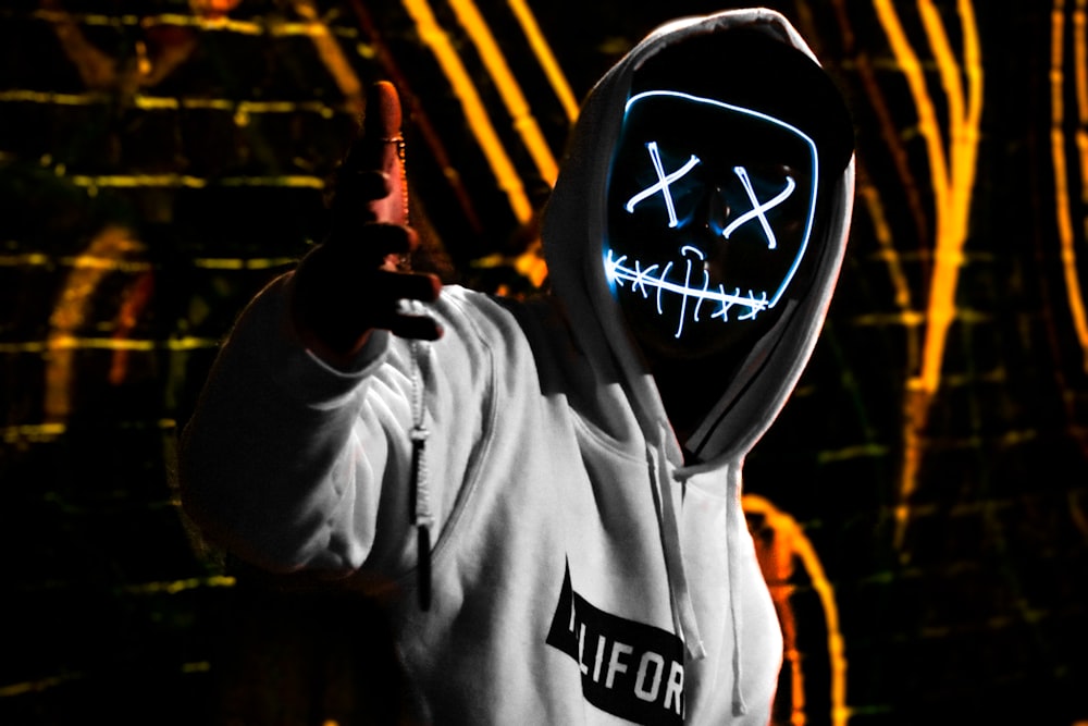 Mann mit weißem California-Pullover-Kapuzenpullover und LED-Maske