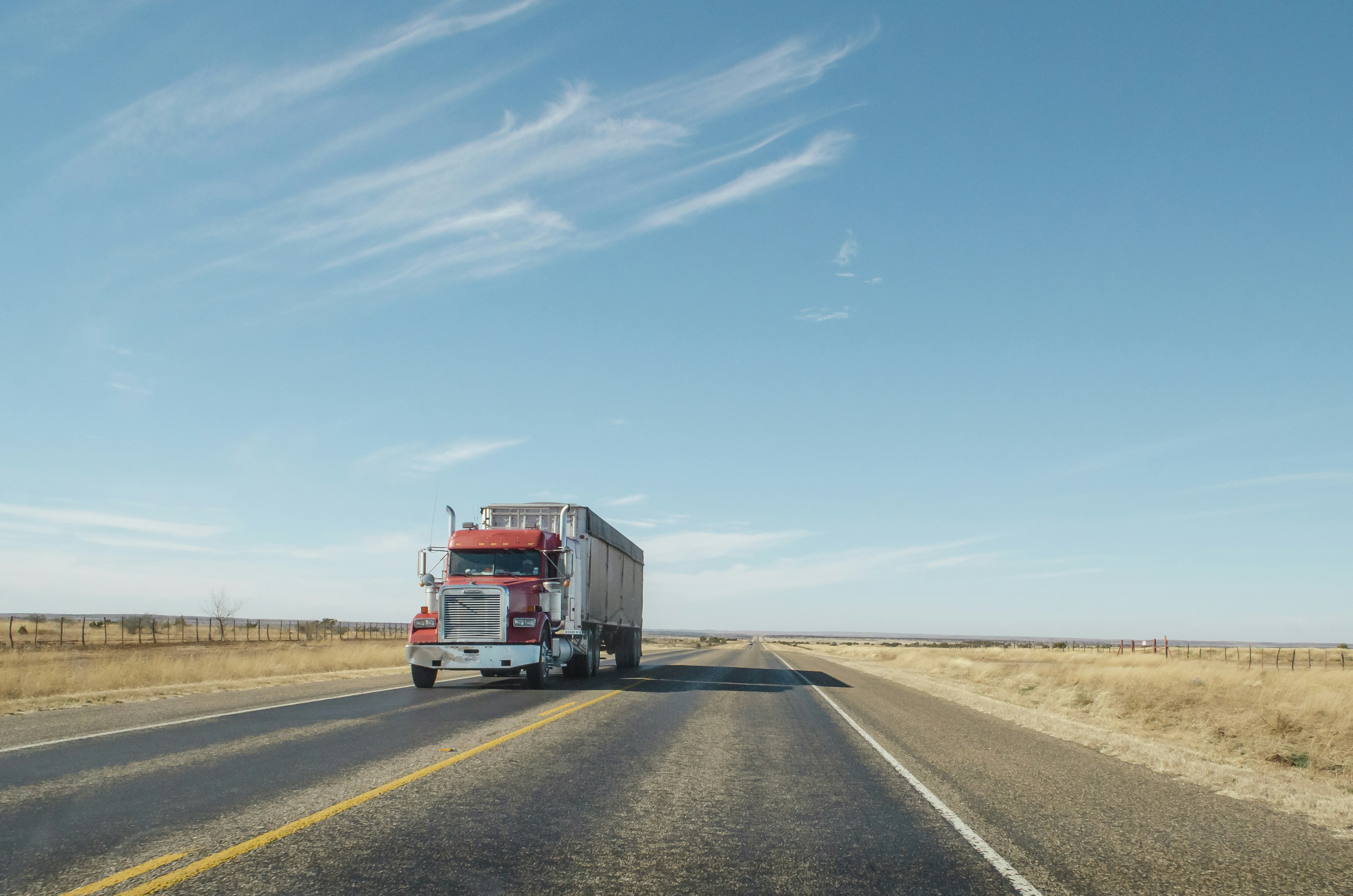 &quot;A red semi truck driving along a West Texas road&quot;