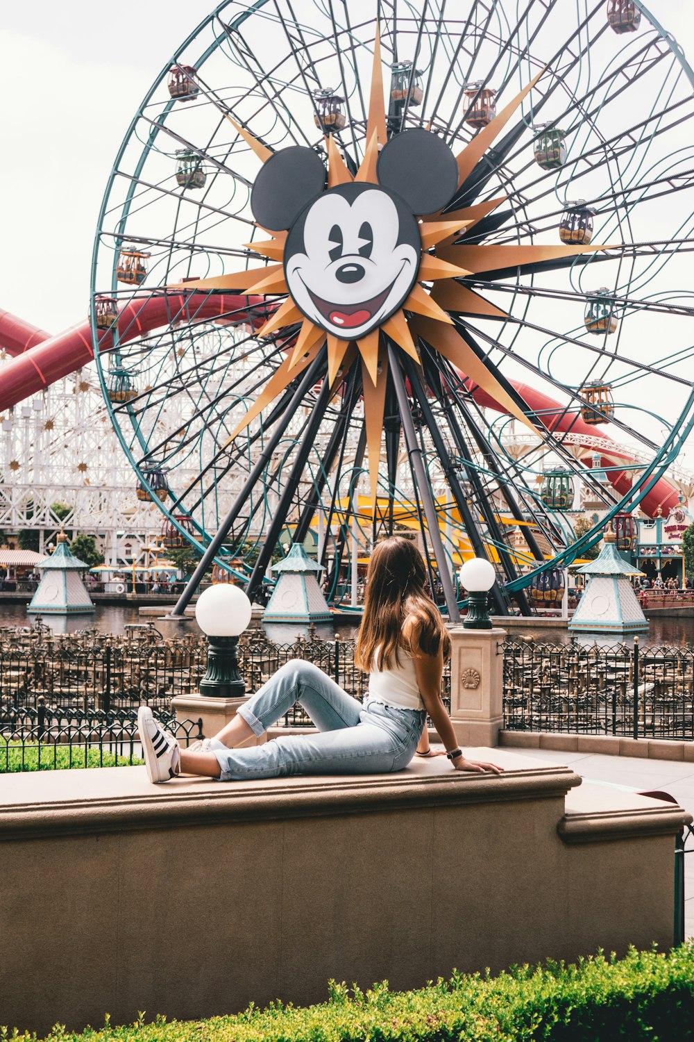 woman sitting on brown concrete table near ferris wheel