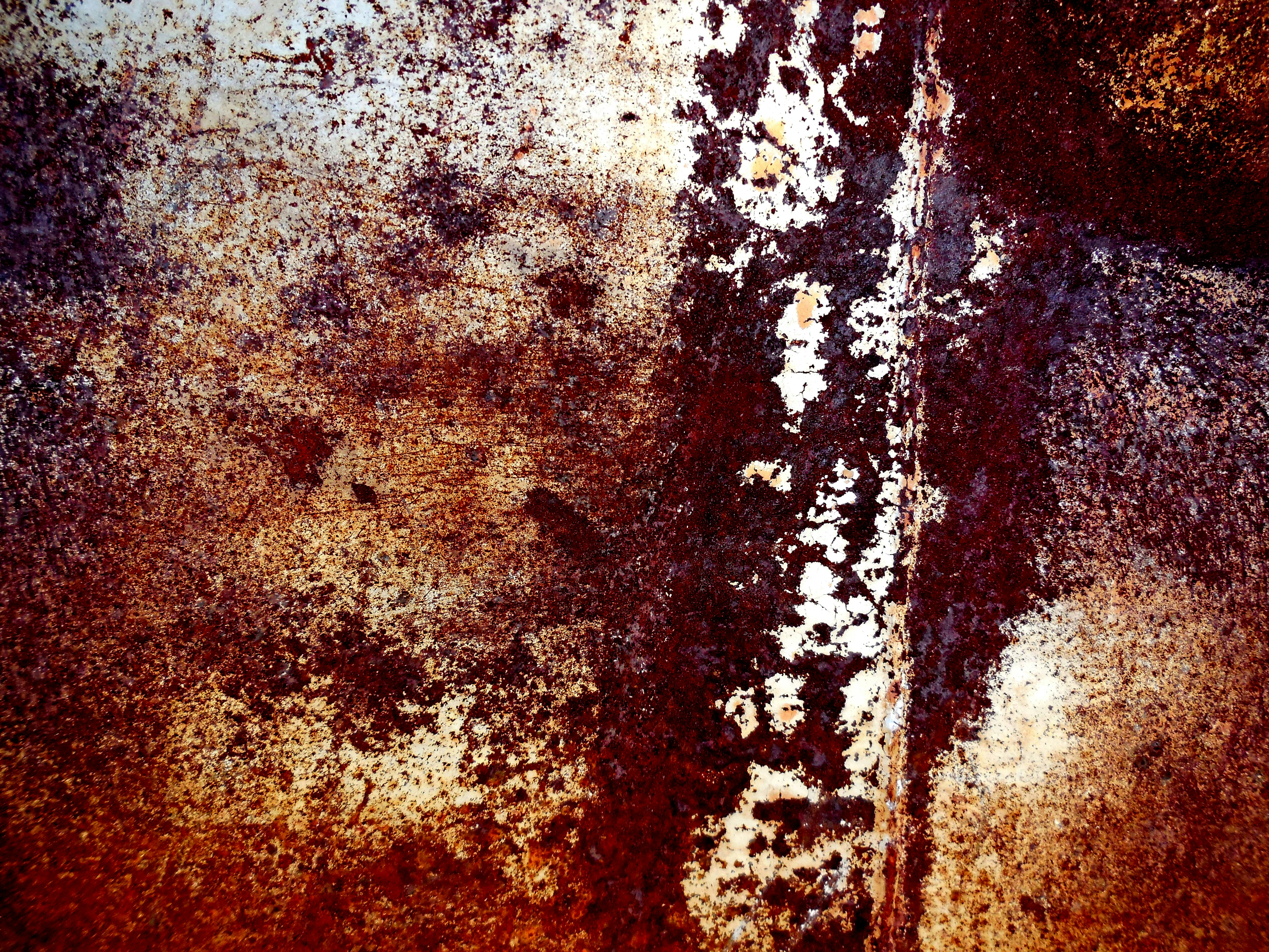 a rusted metal surface with white and brown paint