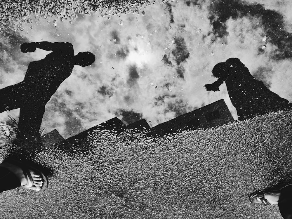 reflection of two people on water puddle