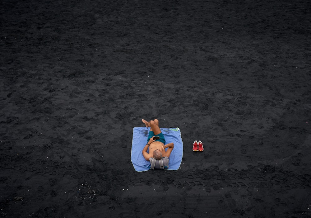 hombre sin camisa acostado sobre una alfombra de picnic azul en el campo