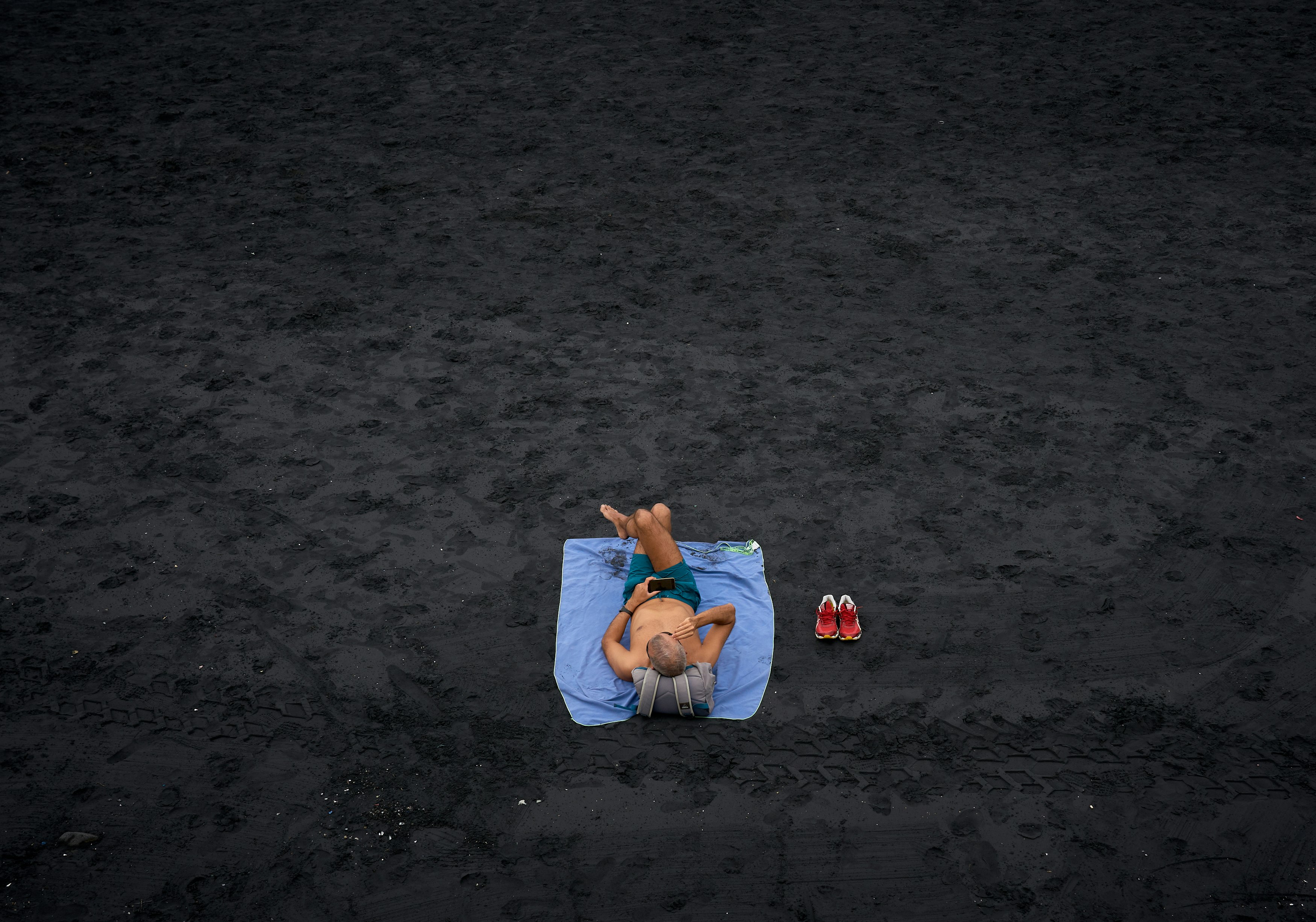 shirtless man lying on blue picnic mat on the field